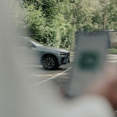 SUV im Hintergrund und vorne Smartphone mit digitalem Schlüssel