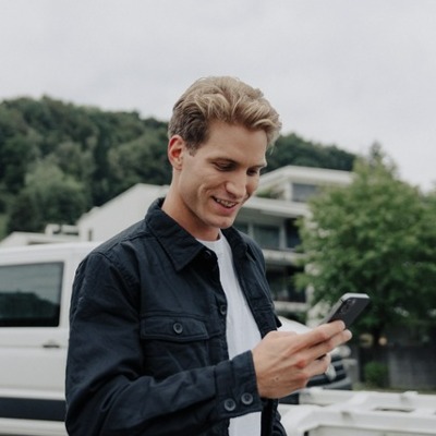 Mann schaut auf Smartphone und lächelt