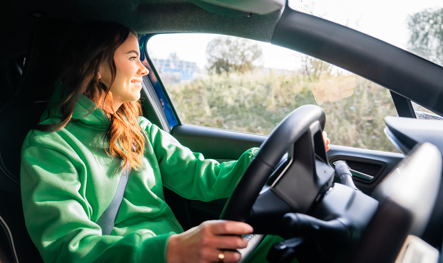 Frau in grünem Outfit am Lenkrad eines Enterprise Minilease Autos Frau in grünem Outfit am Lenkrad eines Enterprise Minilease Autos